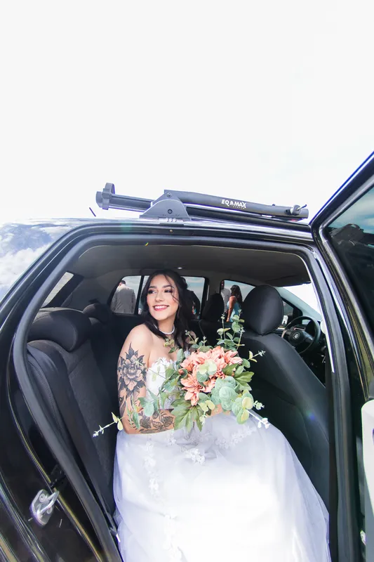 Noiva sentada no carro com o buquê de flores
