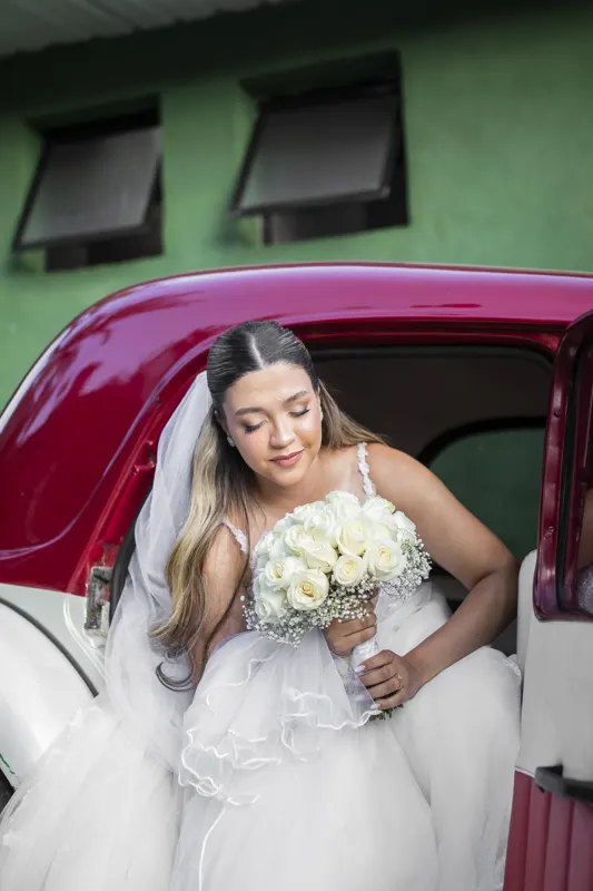 Noiva sentindo o perfume do buquê ao sair do carro antigo