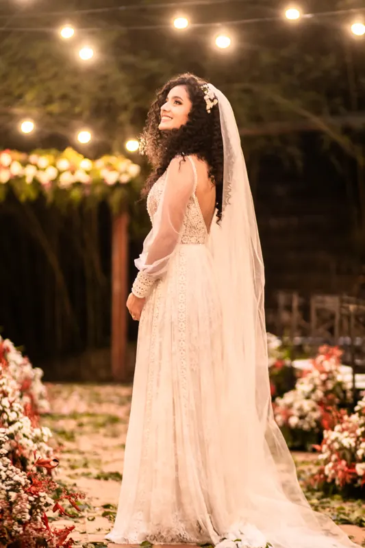 Noiva de costas com véu longo olhando para as luzes