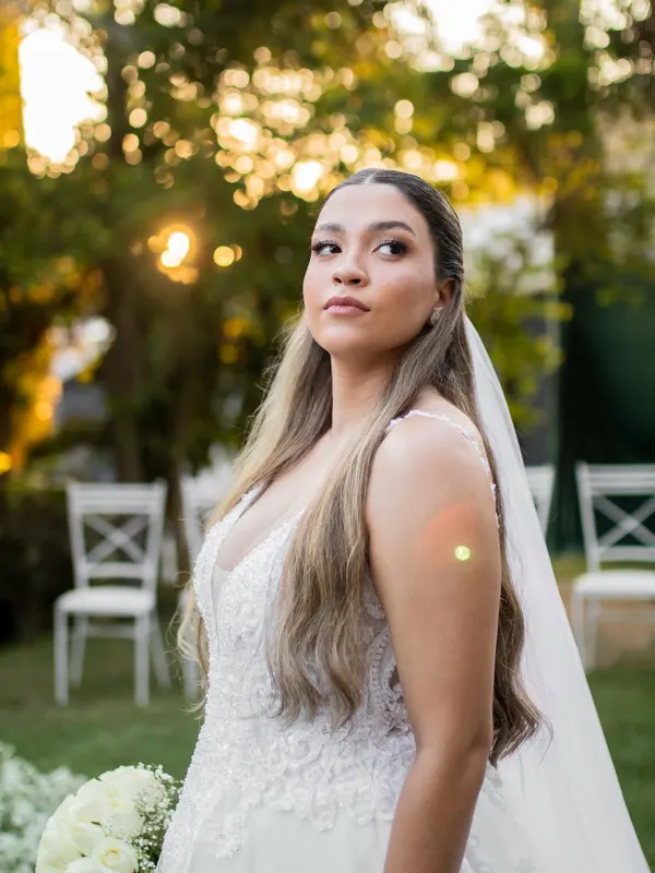 Noiva olhando por cima do ombro com a luz dourada entre as árvores