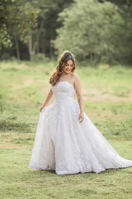 Noiva segurando a saia do vestido no gramado