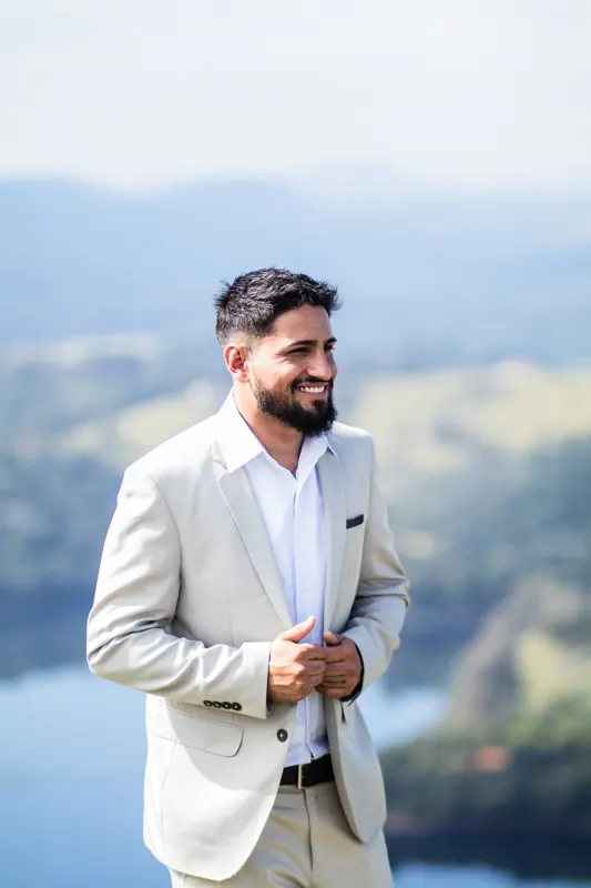 Noivo sorrindo ajeitando o paletó no alto do morro