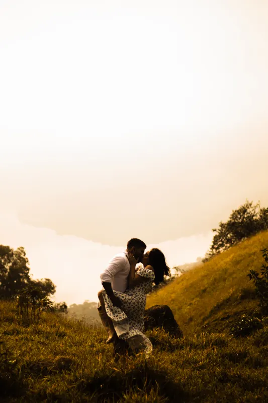 Beijo do casal no morro em tons dourados