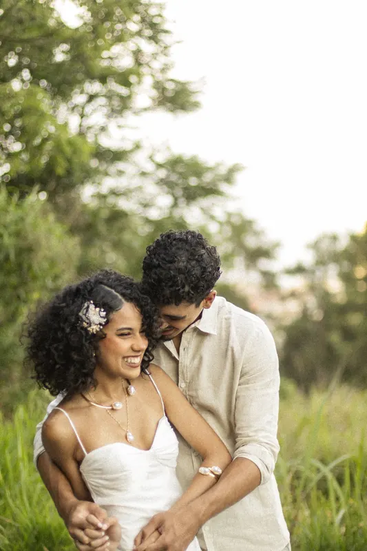 Casal rindo abraçado no campo