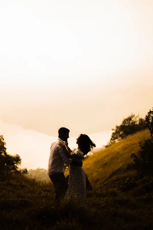 Casal dançando e rindo no morro com o cabelo ao vento
