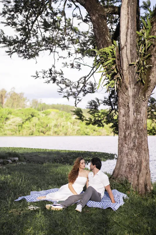 Casal sentado na toalha de piquenique em frente ao lago