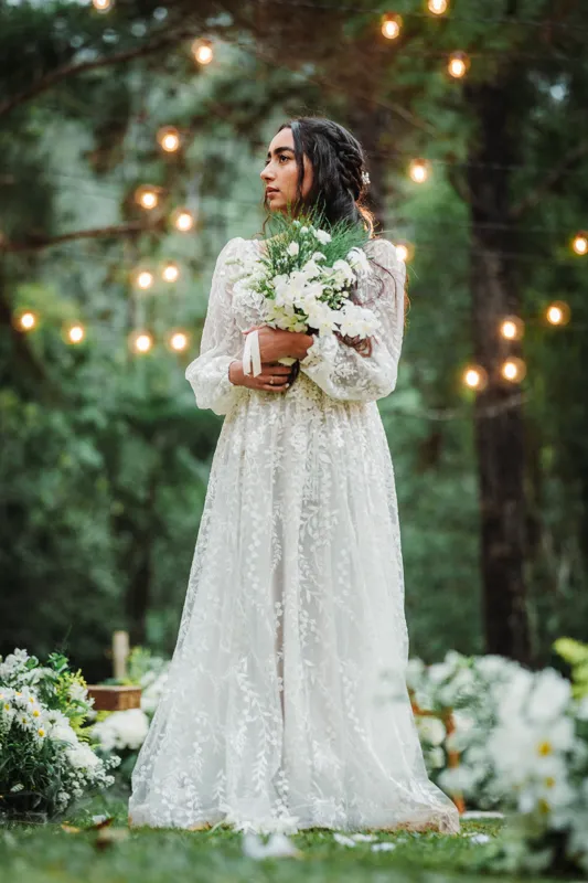 Noiva segurando o buquê de flores brancas no jardim iluminado