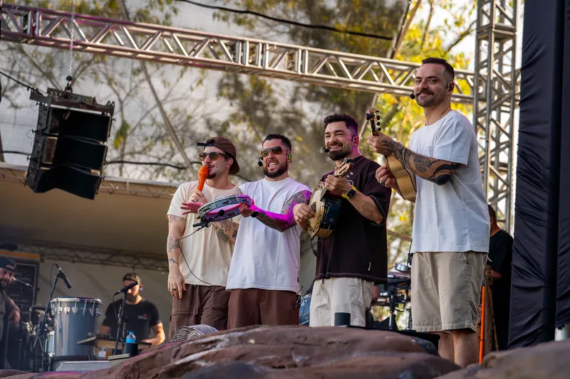 Integrantes da banda rindo juntos no palco
