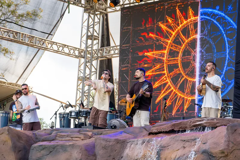 Banda tocando em frente a um telão com um sol laranja