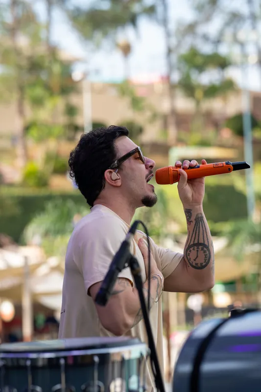 Cantor de perfil cantando com a mão no peito