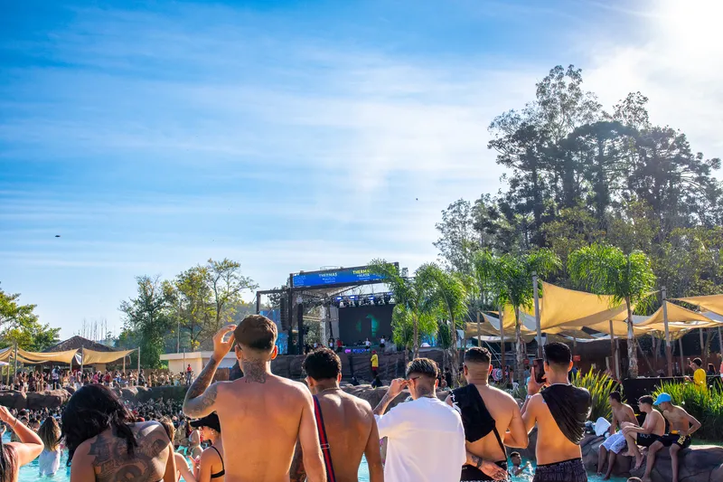 Público de costas olhando para o palco em um dia de sol